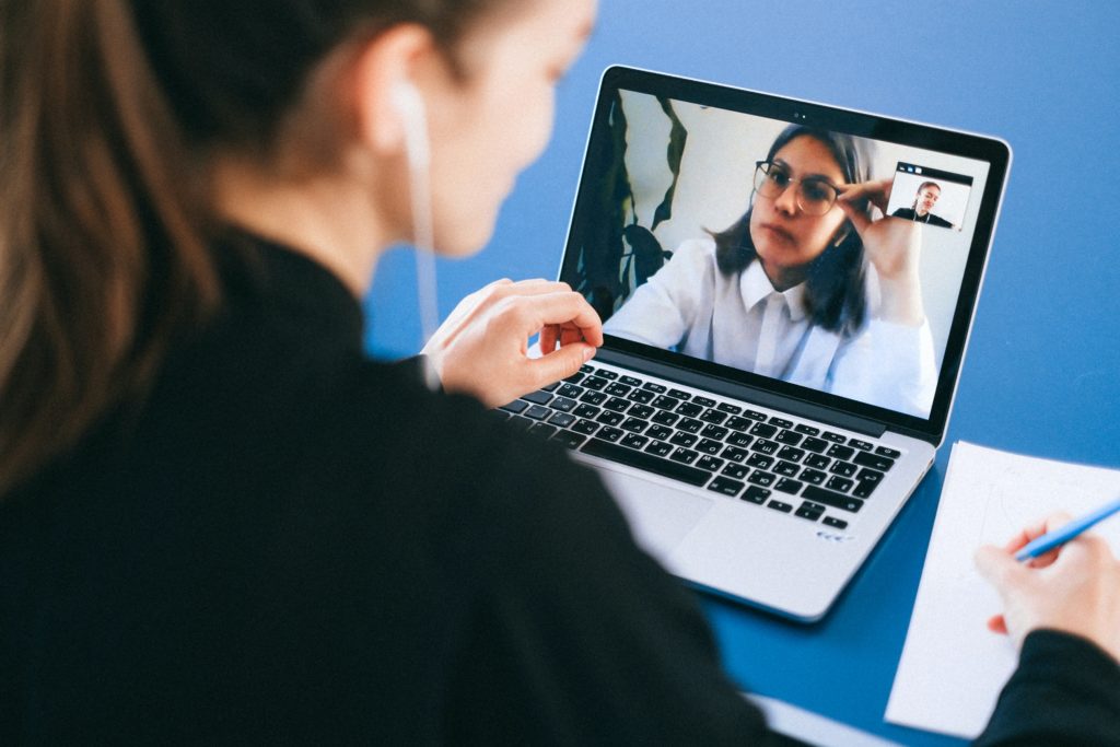 Woman talking via to a woman on a computer monitor.