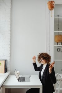 Staff member celebrating a moment with raised hands at a desk